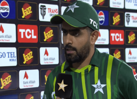 Babar Azam, dressed in the Pakistan cricket team's uniform, addressing the media with a microphone in hand after a cricket match.