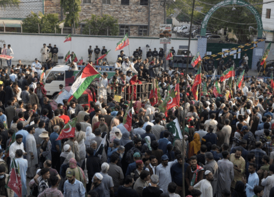 PTI supporters holding banners and flags during a protest, passionately voicing their demands in a public square.