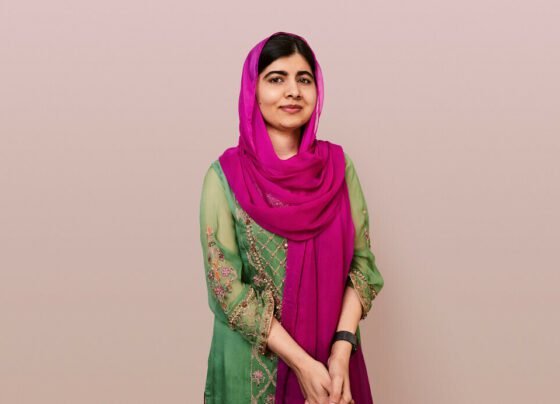 Malala Yousafzai standing confidently, wearing a vibrant traditional South Asian outfit